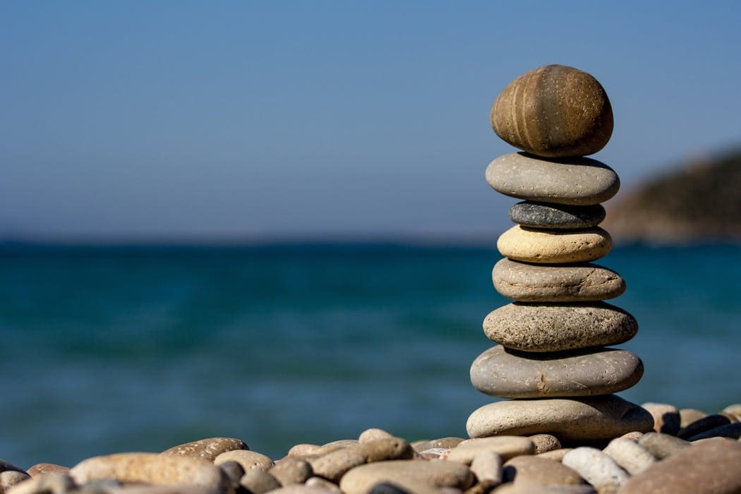 A stack of rocks on the beach near water.